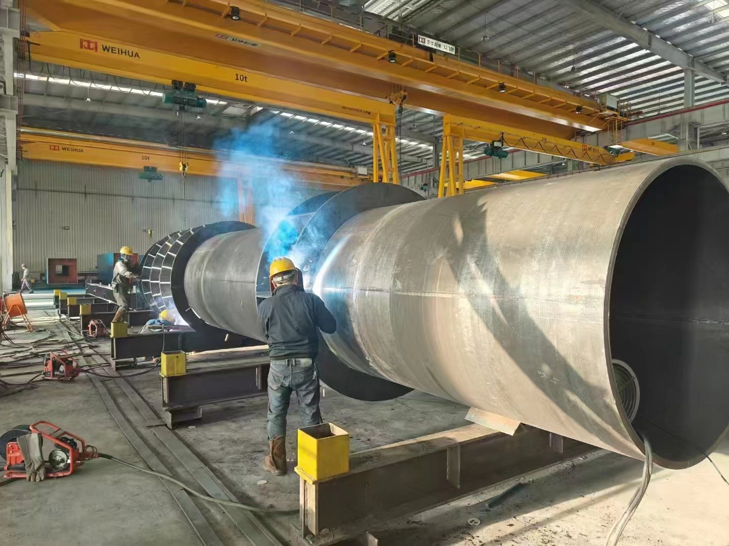 Worker welding a large diameter tubular steel column