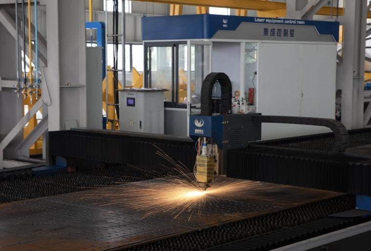 Numerically controlled cutting machine profiling a steel plate beside the control room